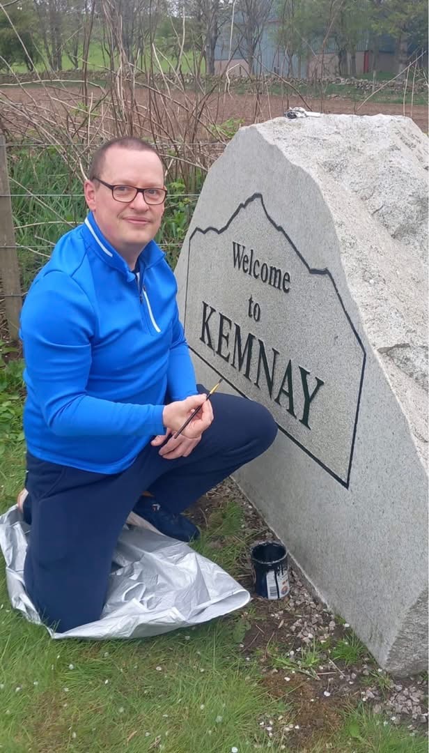 Member repainting the Welcome to Kemnay stone sign