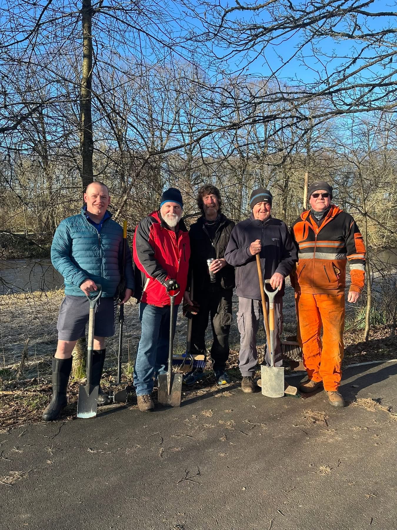 Members of Kemnay Men's Shed by the riverside with tools after a community workday