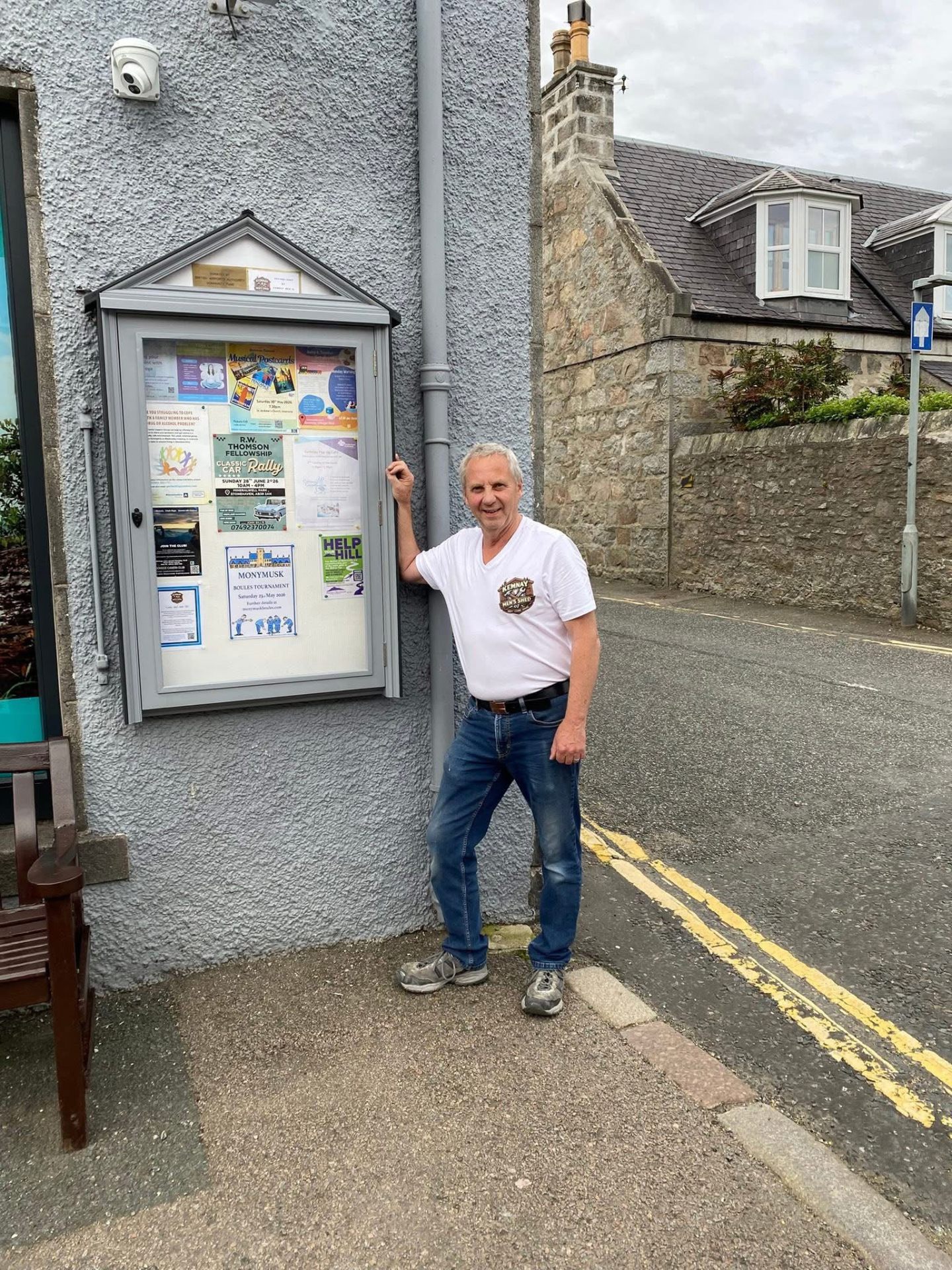 Member beside the new community notice board installed at the Chemist in Kemnay
