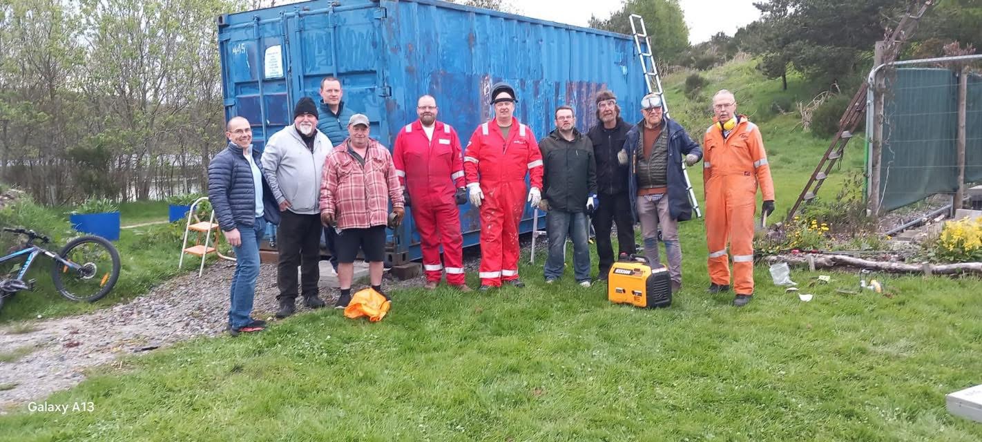 Members gathered outside the shed's storage container
