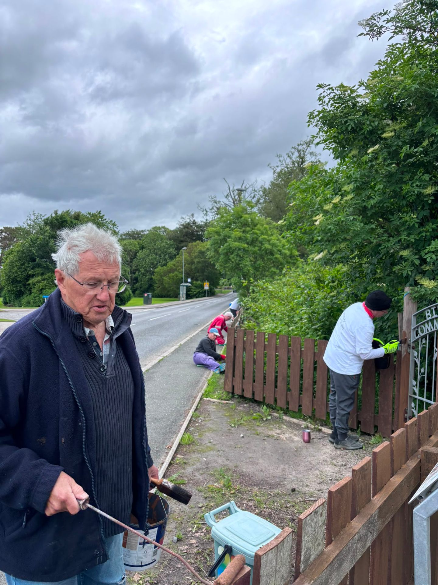 Members painting the Birleybush garden fence by the roadside